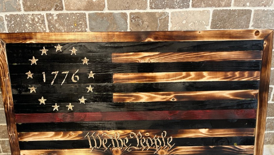1776 charred heritage flag with Thin Red Line and We the People carving